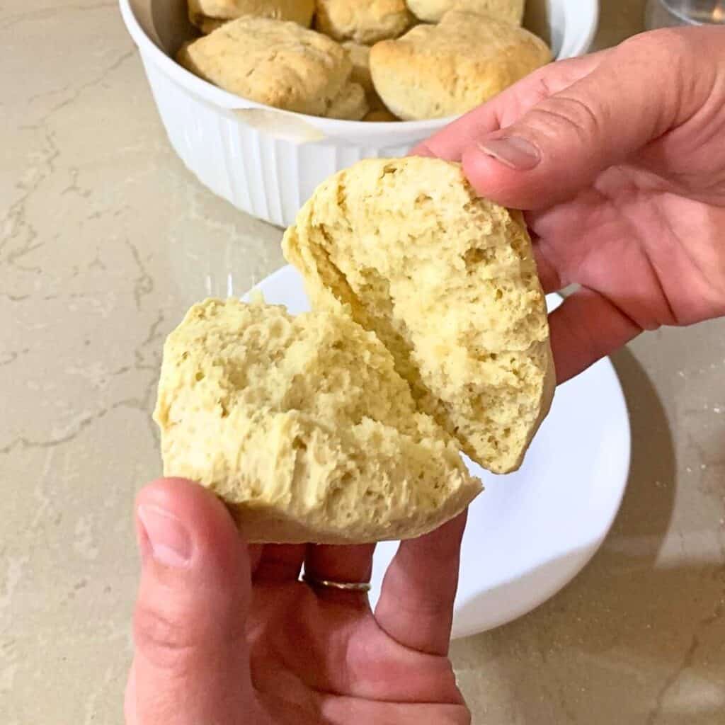 Woman pulling apart a homemade biscuit, made with 3 ingredients without milk.
