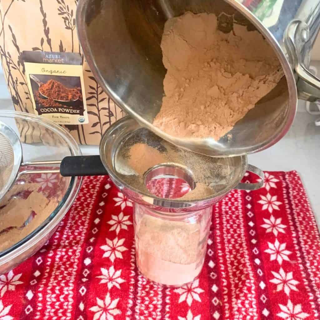 Woman pouring hot chocolate mix into a glass jar.