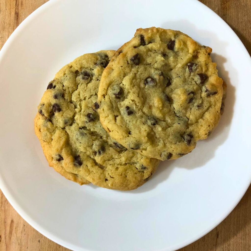 Two chocolate chip cookies on a white plate.