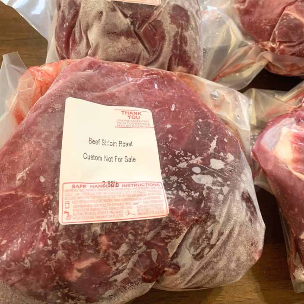 A frozen sirloin tip roast sitting on a wood table.