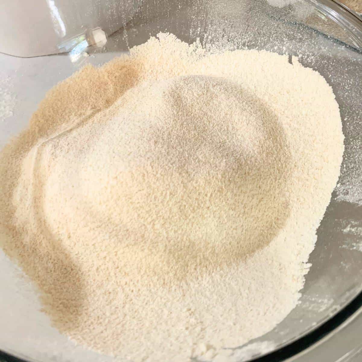 Fine flour in a glass bowl on a kitchen counter.