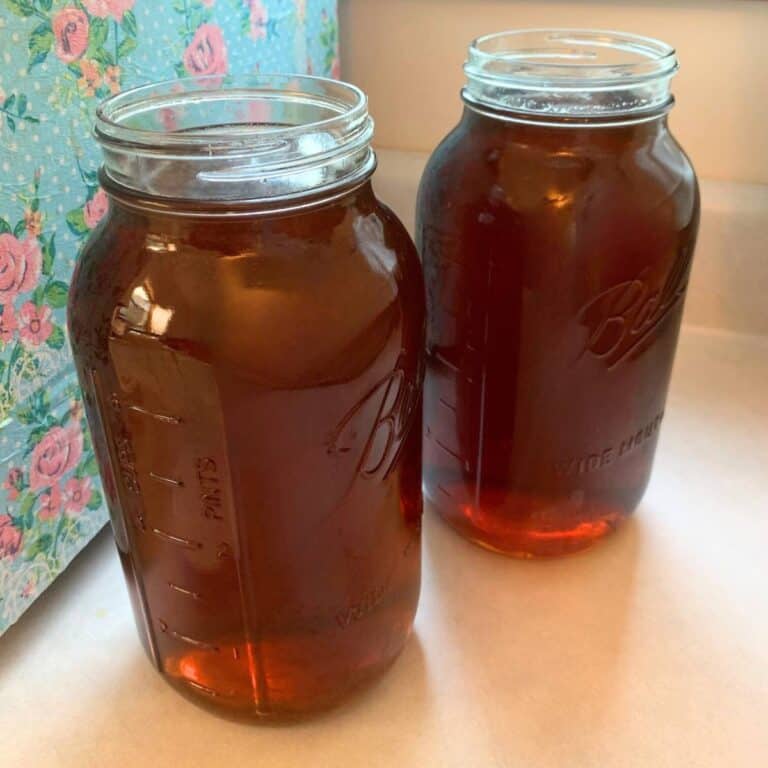 Two half-gallon mason jars of organic peach tea sitting on a counter.