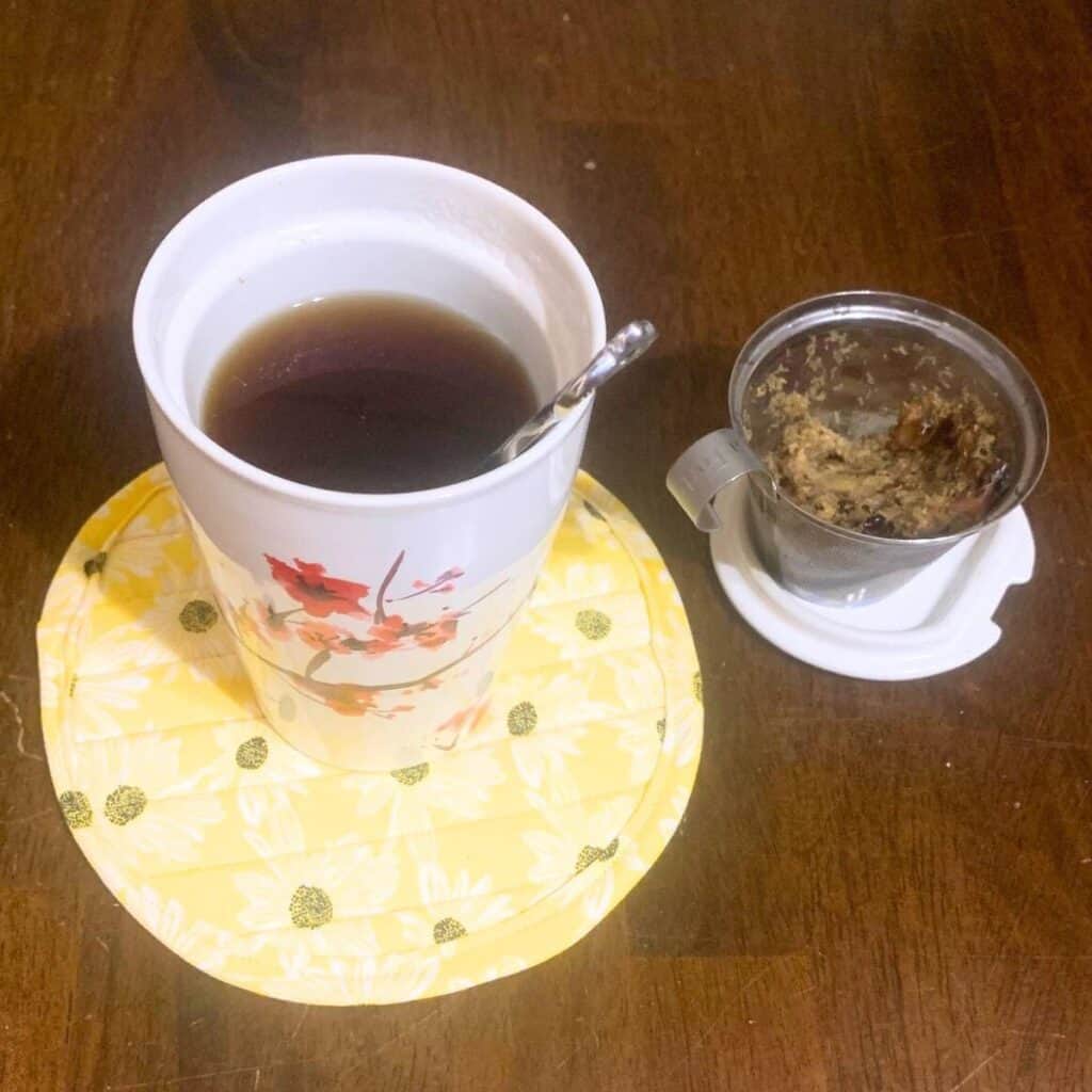 Herbal tea sitting on a yellow coaster on a wood table. How to Start Homesteading