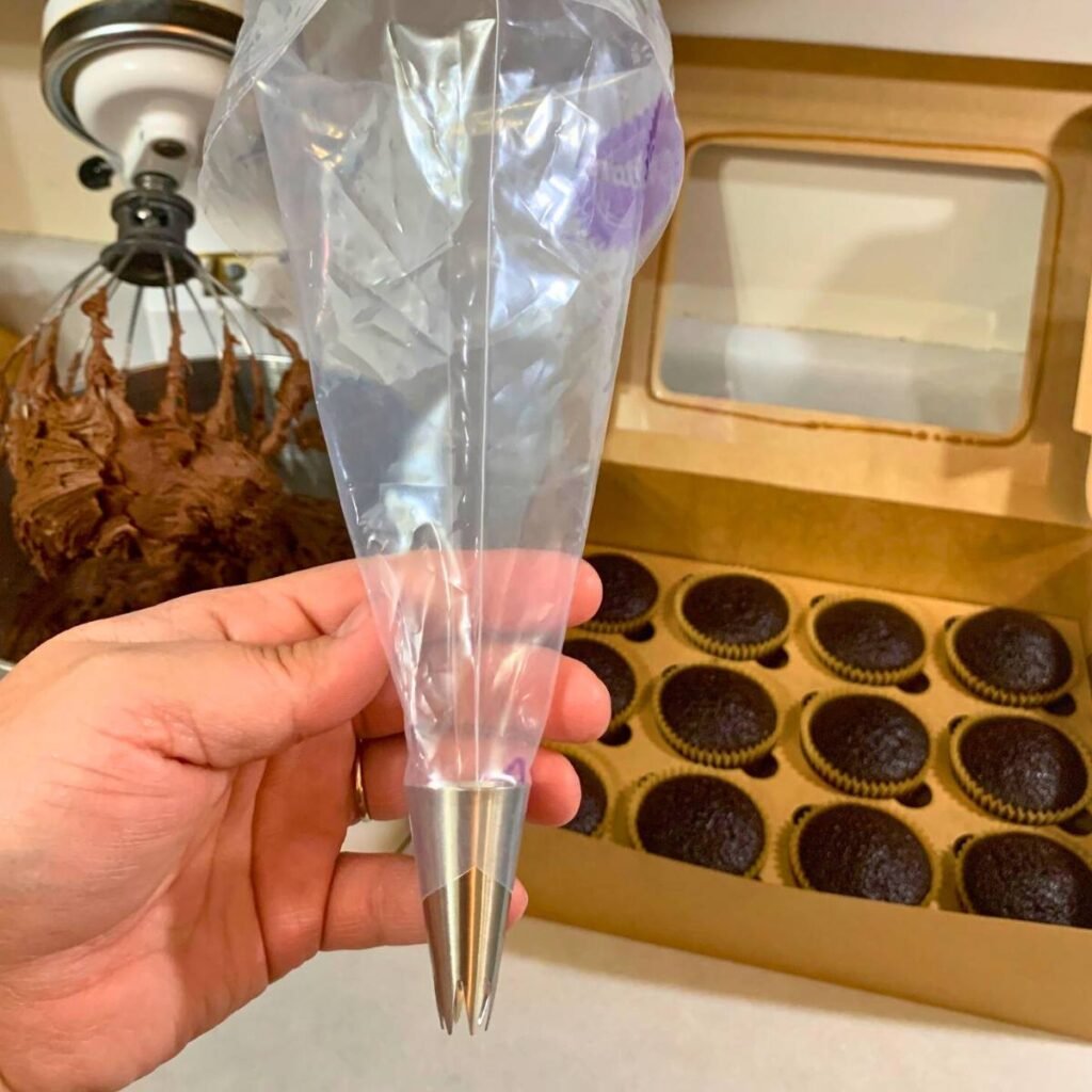 Woman holding an empty Wilton plastic piping bag with star tip inserted at the tip of the bag.