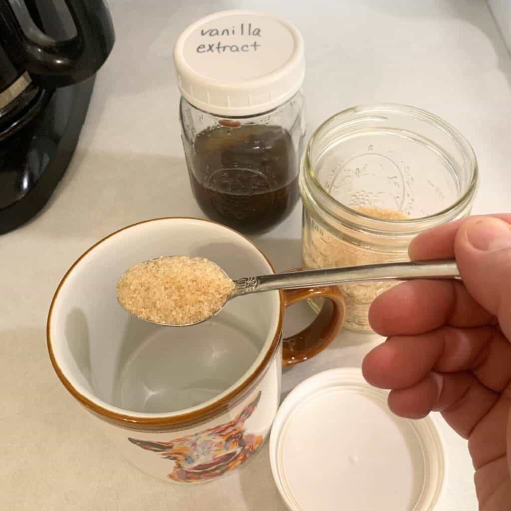 Woman adding sugar to a coffee cup.