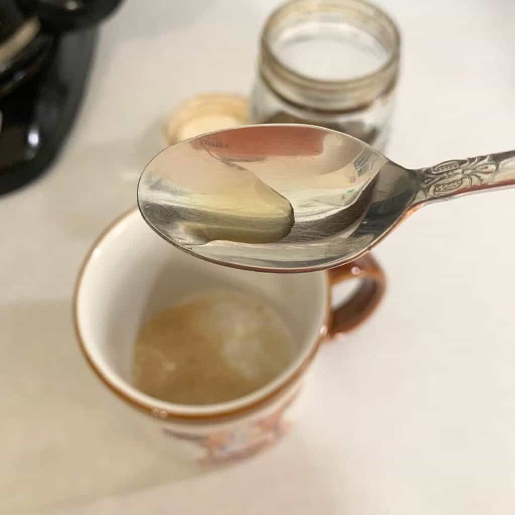 Woman using vanilla extract in coffee.