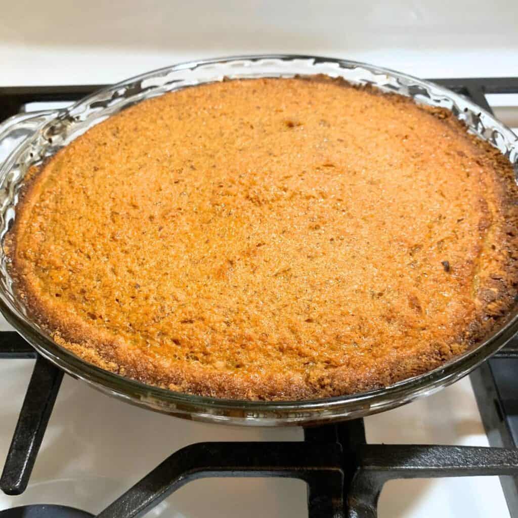 Low sugar carrot pie in a glass pie dish sitting on a gas stove.