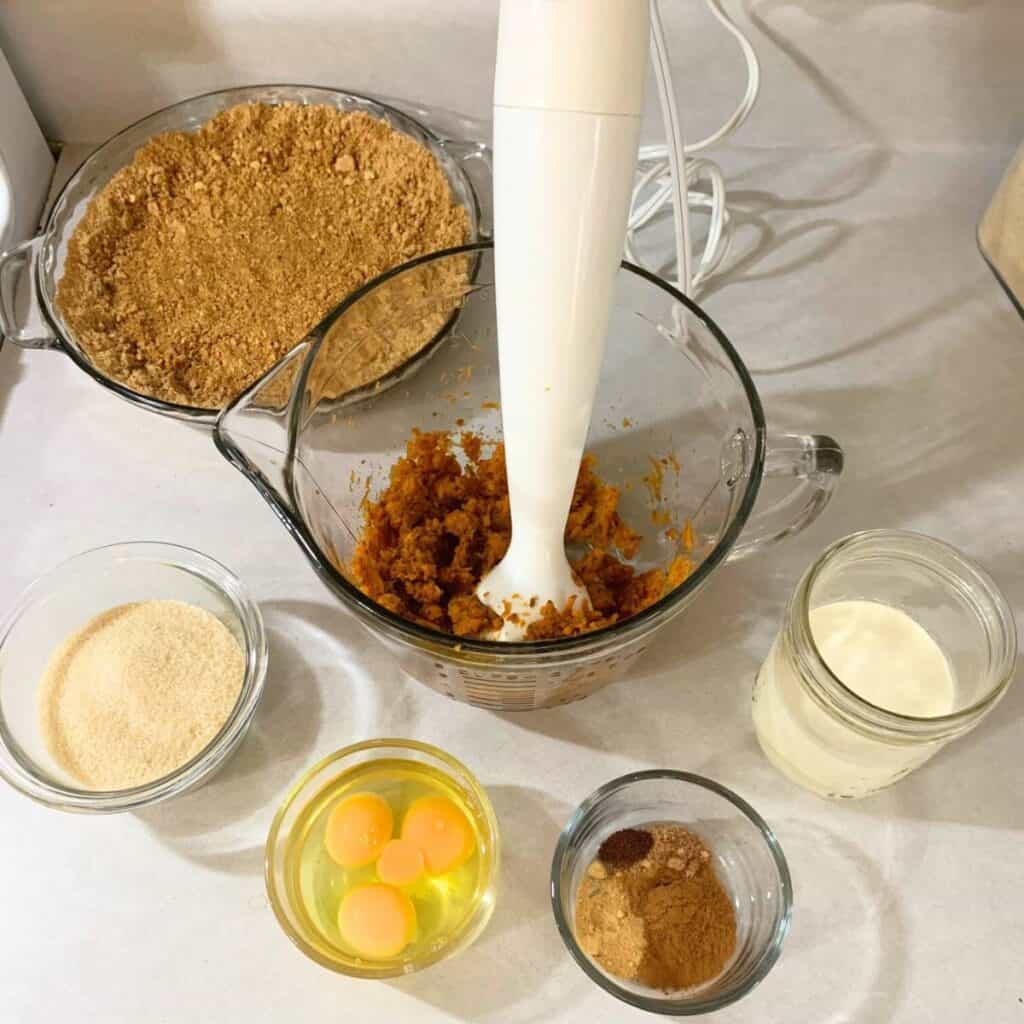 Woman pureeing steamed carrots in a glass mixing bowl.