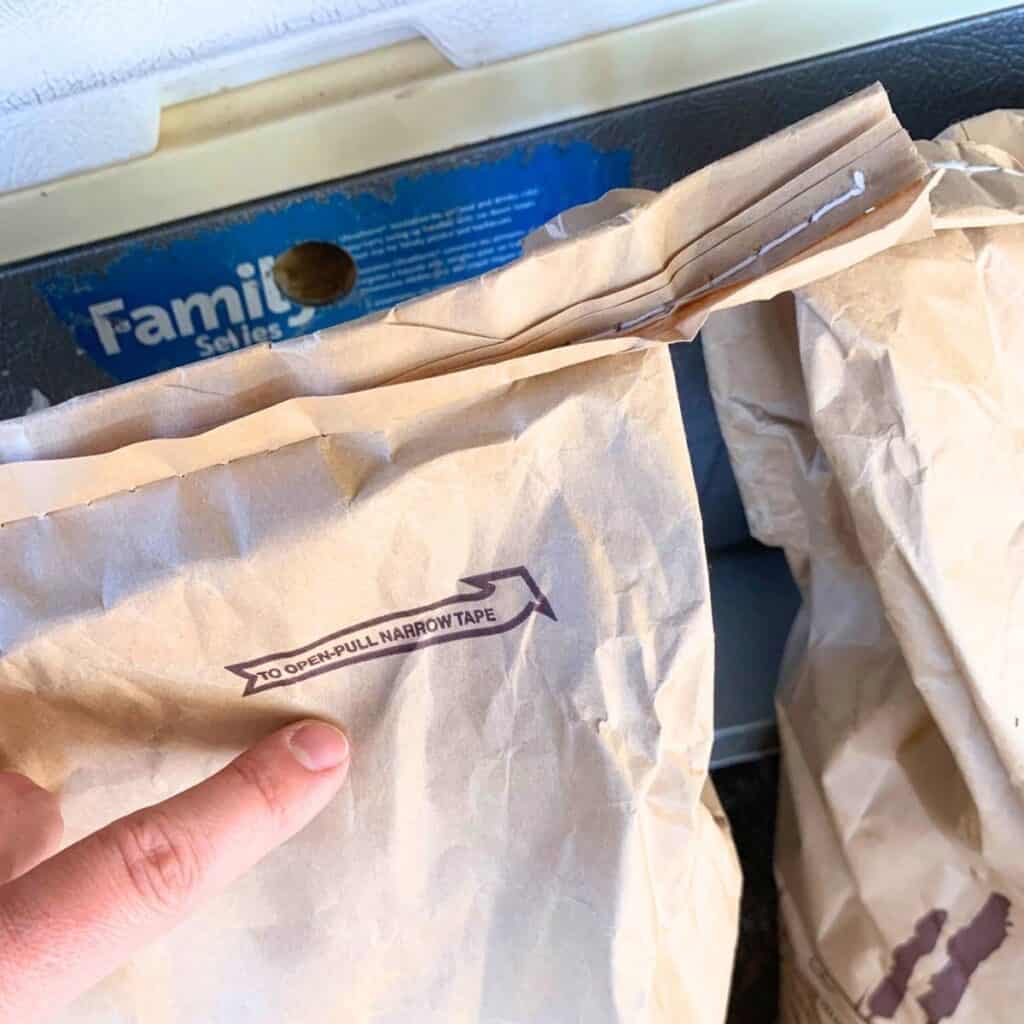 Woman pointing to the top of an animal feed bag, showing the tab to pull to open the bag.