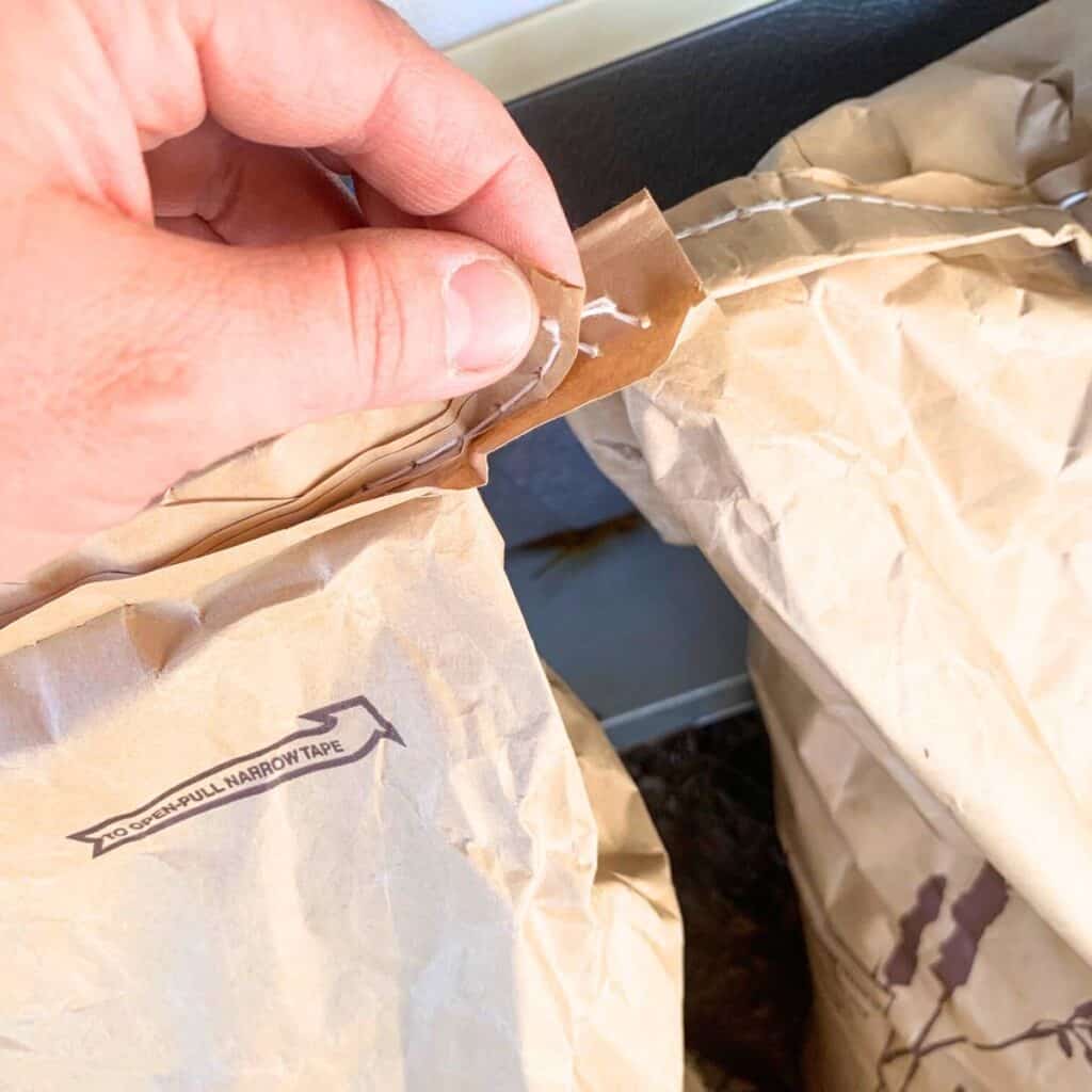 Woman pulling tape and string on the top of an animal feed bag.