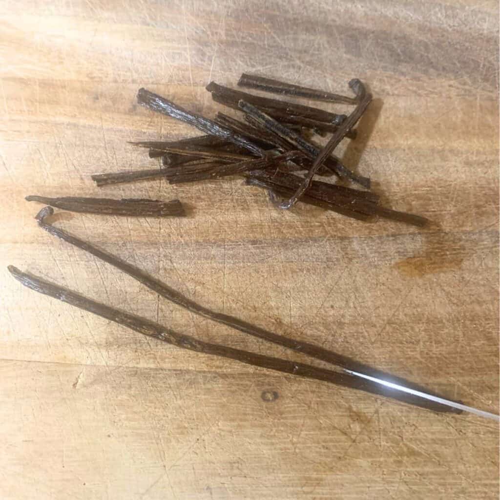 Woman cutting a vanilla bean in half lengthwise.