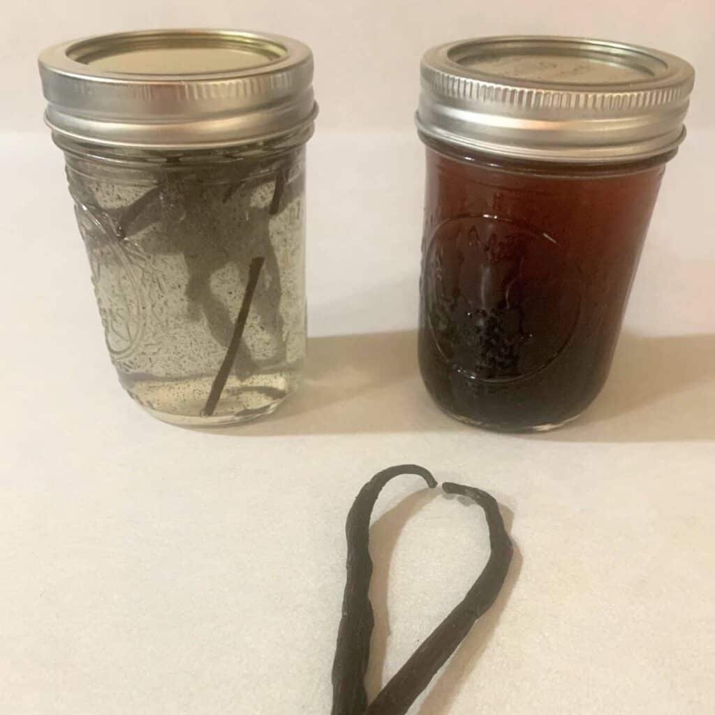 Two glass pint jars of alcohol free vanilla extract sitting on a kitchen counter next to two whole vanilla beans.