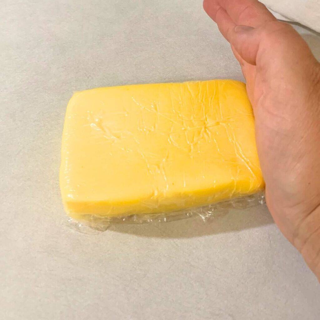 Woman smoothing sides of homemade butter.
