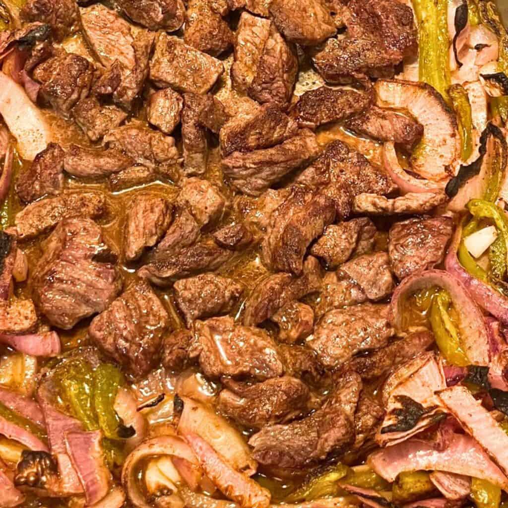 A plate of steak fajitas with mixed onion and peppers.