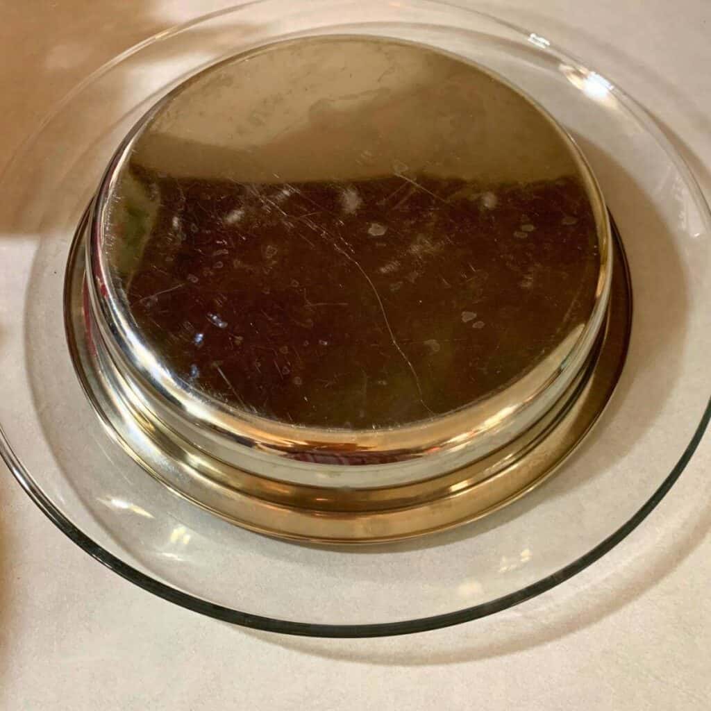 A round cake pan turned upside down on a glass plate stand.