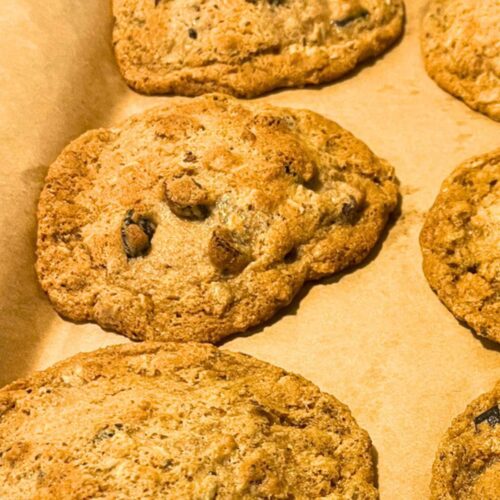 Freshly baked cowboy cookies sitting on a cookie sheet lined with parchment paper.