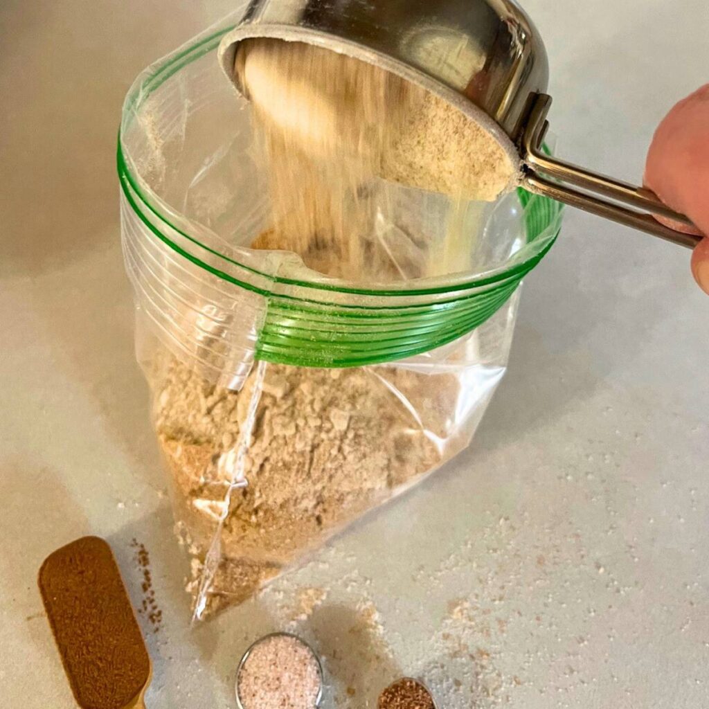 Woman pouring sugar into a zip top bag with flour inside. 