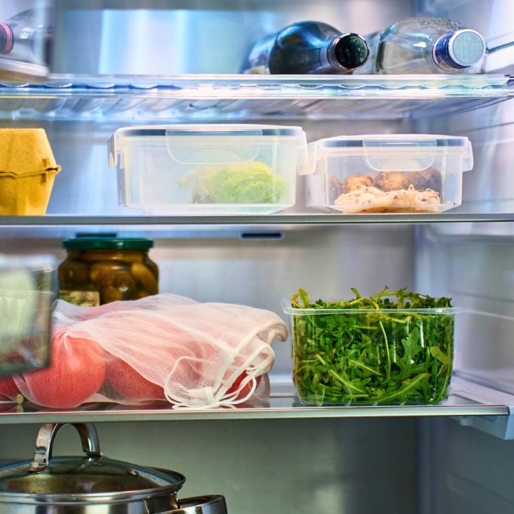 A refrigerator with items including sliced turkey breast in an airtight container.